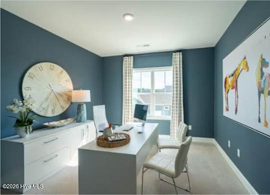 A room with a desk, chair, and a large clock on the wall.