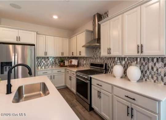 A kitchen with white cabinets and a black and white tiled backsplash.