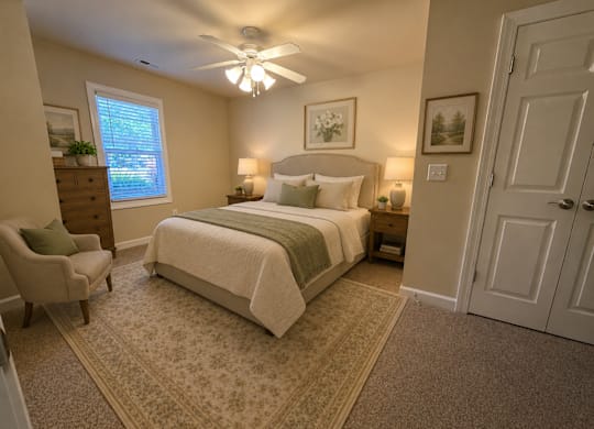 A bedroom with a bed, chair, and ceiling fan.