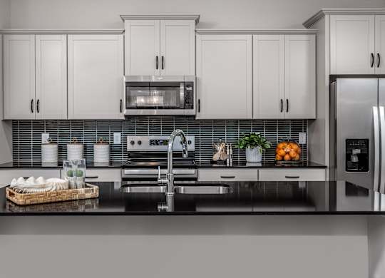 A modern kitchen with white cabinets and a black countertop.
