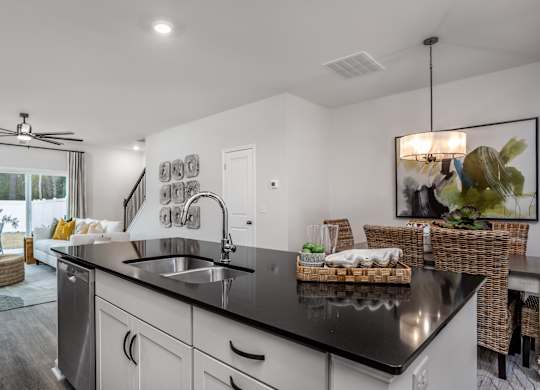 A modern kitchen with a black countertop and stainless steel appliances.