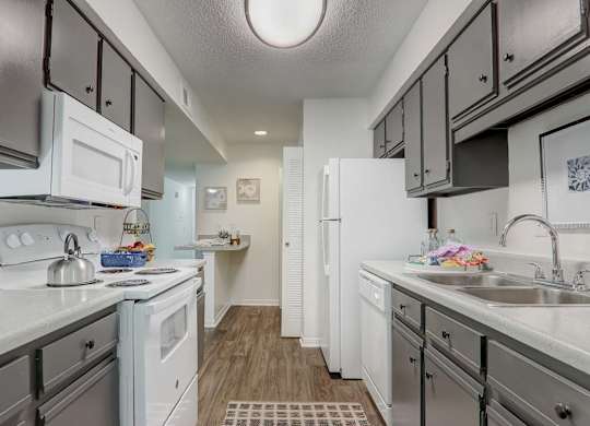 A kitchen with white appliances and grey cabinets.