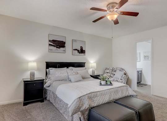 A bedroom with a bed, nightstand, and a ceiling fan.