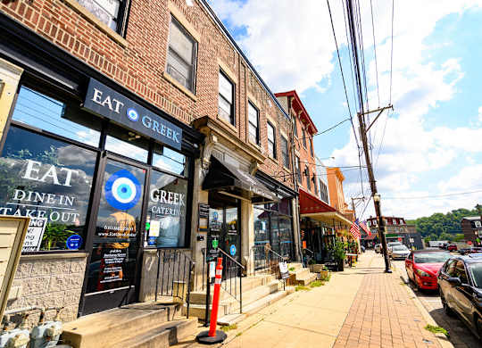 a city street with shops and cars parked on the sidewalk