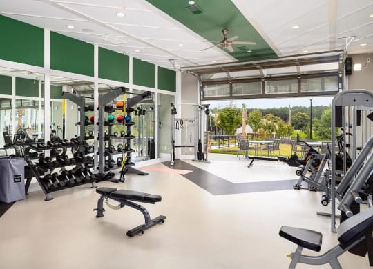 Fitness Center with the garage door open leading to patio seating outside at Carmel Vista, McDonough, GA