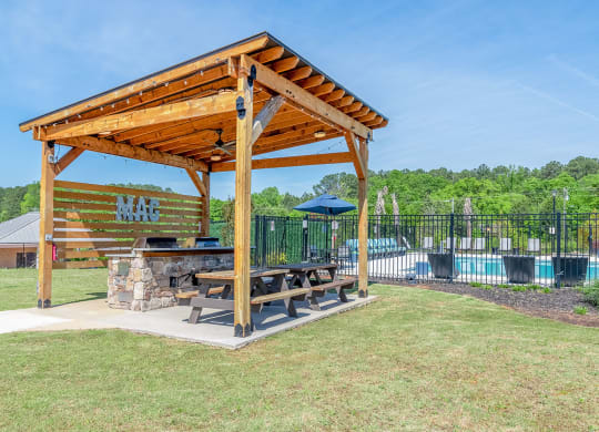 a picnic table under a wooden pavilion next to a swimming pool at Carmel Vista, McDonough, Georgia