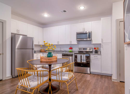 a kitchen with white cabinets and a table and chairs at Carmel Vista, McDonough, Georgia