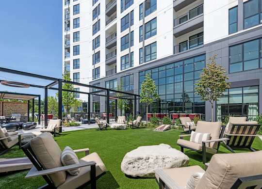 a lounge area with chairs and a lawn in front of a tall building
