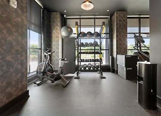 a workout room with a bike and weights on a rack
