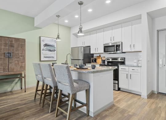 a kitchen with an island and three bar stools at Inspira, Naples, FL