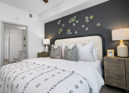 a bedroom with a bed and a grey wall and a bathroom at Inspira, Naples, Florida