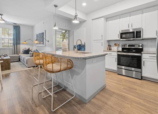 an open kitchen and living room with an island and chairs at Inspira, Naples, FL