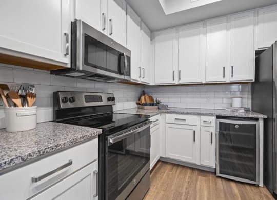 a kitchen with white cabinets and stainless steel appliances including a wine refrigerator at Inspira, Florida, 34113