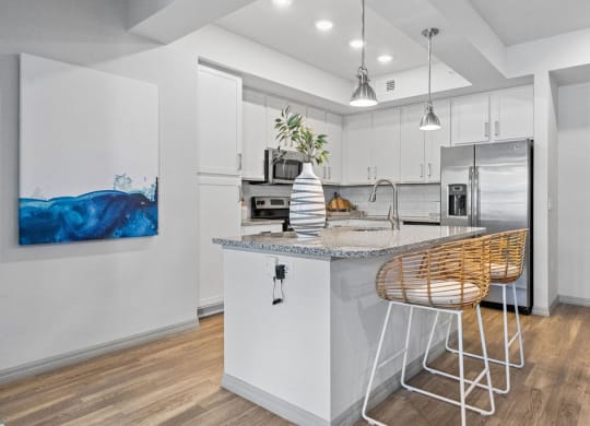 a kitchen with an island and a bar with stools at Inspira, Naples, FL, 34113