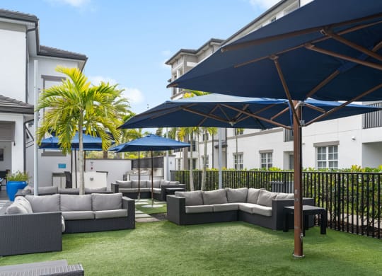 a lounge area with couches and umbrellas on a lawn at Inspira, Naples, FL, 34113