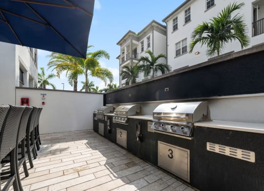 three barbecue grills on a patio in front of a building at Inspira, Naples, Florida
