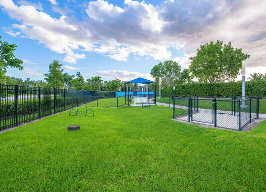 a fenced in dog park with a playground and a gazebo at Inspira, Naples, Florida