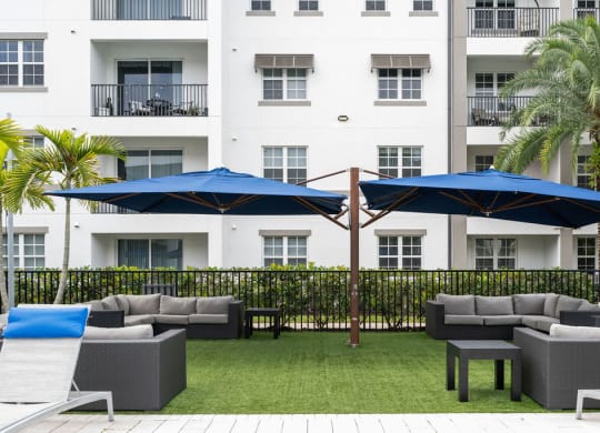 a patio with couches and umbrellas in front of a building at Inspira, Naples, FL, 34113