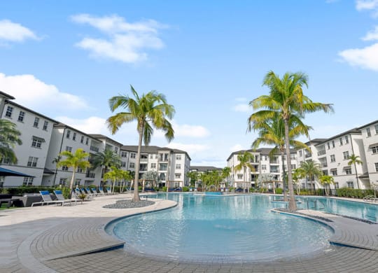 Palm trees flanking either side of the pool in the center of the apartment home buildings at Inspira, Naples, 34113