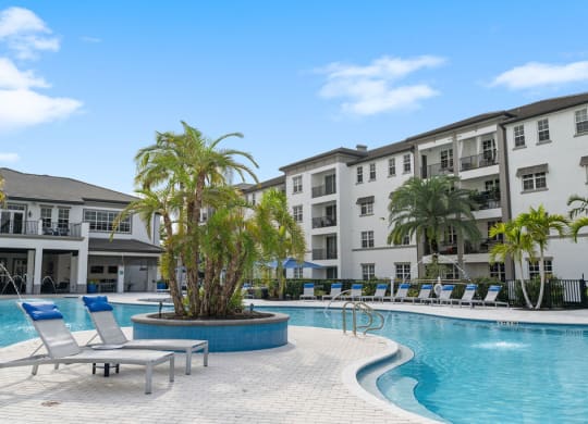 The pool with many lounge chairs and islands with palm trees at Inspira, Naples, FL