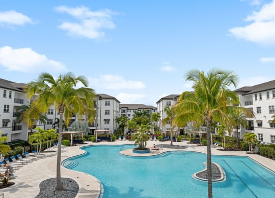 a large swimming pool with palm trees in front of some apartment buildings at Inspira, Naples, Florida