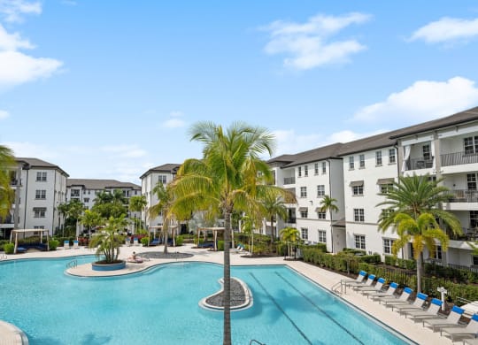 a large swimming pool with palm trees in front of apartment buildings at Inspira, Naples, 34113