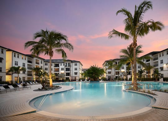a large swimming pool with palm trees at sunset at Inspira, Naples, FL