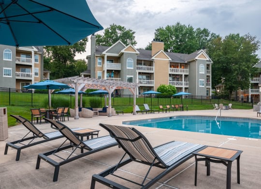 Lounge chairs at the pool looking out toward cabana and apartment building in the distance at Madison Glen Mills, Pennsylvania, 19342