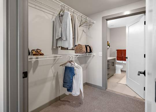 a walk in closet in a bedroom with a door to the bathroom