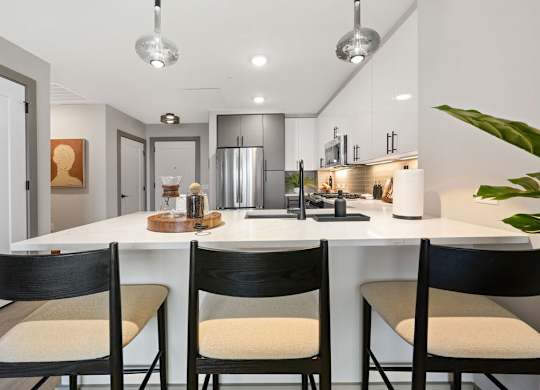 an open kitchen with an island and three chairs