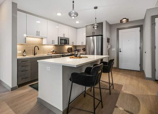 a kitchen with a large island with three chairs