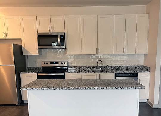 A kitchen with a granite countertop and white cabinets.