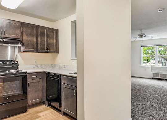 A kitchen with dark brown cabinets and a stainless steel oven.