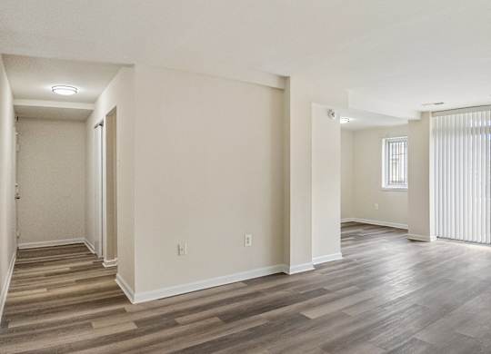 A spacious room with wooden flooring and white walls.