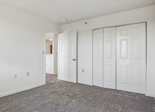 A room with white walls and a grey carpet.