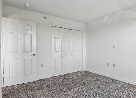 A room with white doors and a grey carpet.
