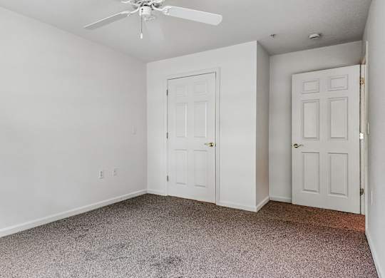 A room with a ceiling fan and two doors.