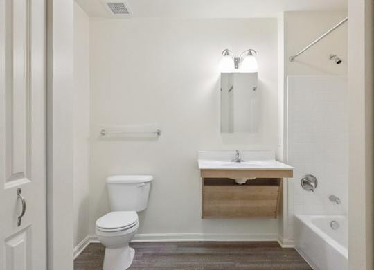 A white bathroom with a toilet, sink, and mirror.