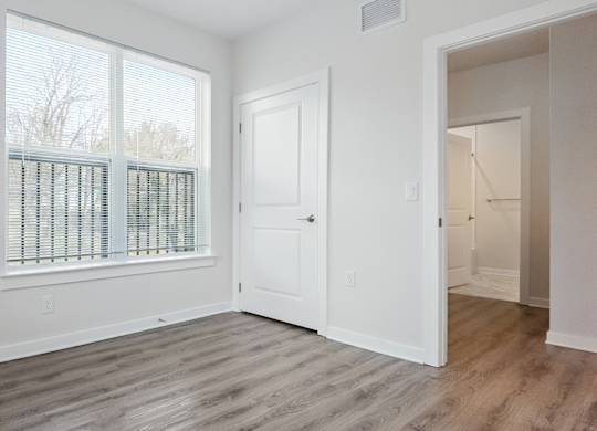 A room with a white door and a window with blinds.