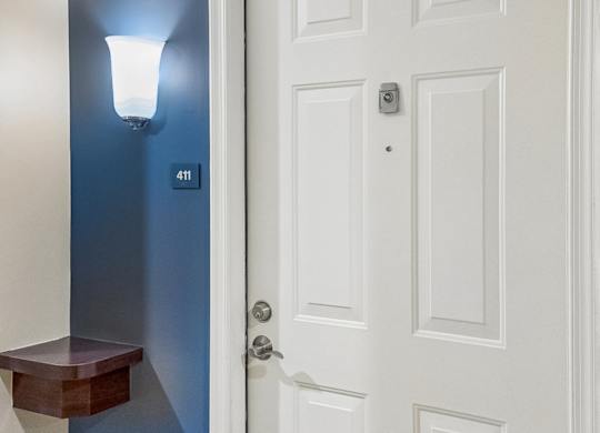 A white door with a silver handle and a small light on the wall.
