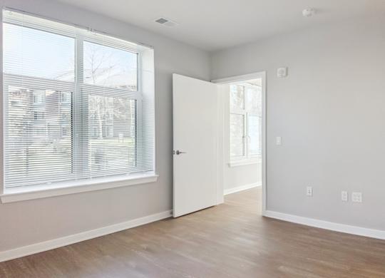 A room with a white door and a window with blinds.