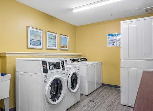 A laundry room with washers and dryers and a clock on the wall.