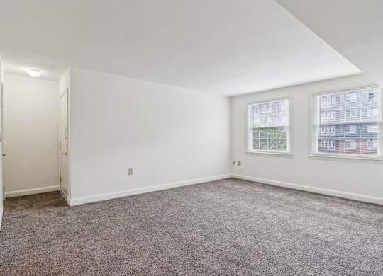 Living room in Towson senior apartment with two windows and neutral carpet