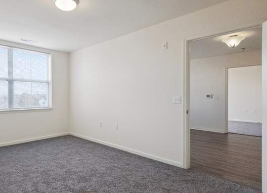 A room with a large window and a carpeted floor.