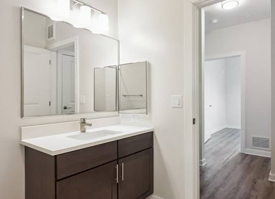 A bathroom with a sink, mirror, and wooden floor.
