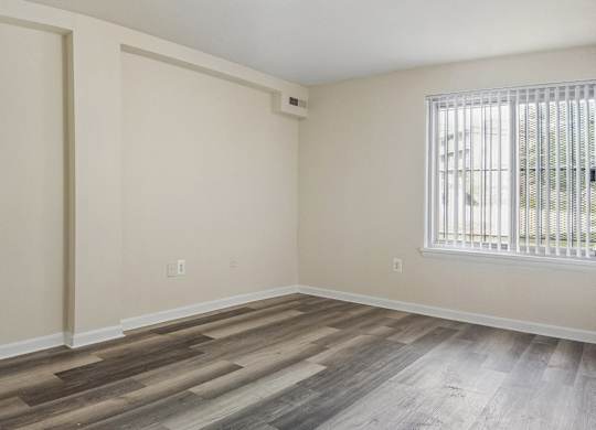A room with wooden flooring and a window with blinds.