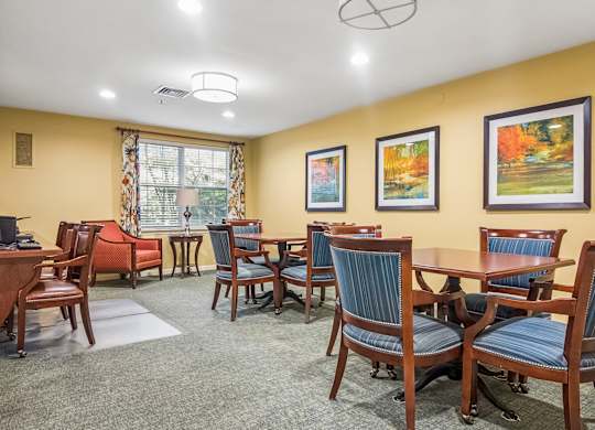 A room with a table and chairs and a painting on the wall.