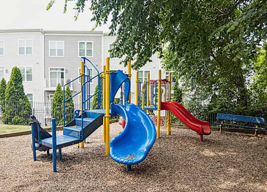 A playground with a blue slide and a red slide.