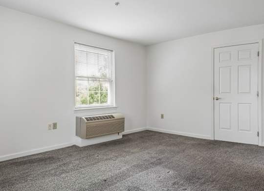 A room with a window, air conditioner, and two doors.