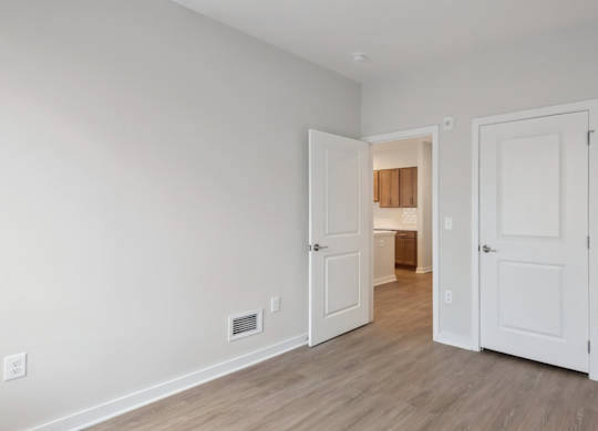 A room with two white doors and a wooden floor.